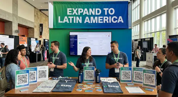 Foto do booth no SXSW Austin: banner grande "Expand to Latin America", tela com demo ao vivo, 3 pessoas no booth conversando com visitantes. Mesa com swag e QR codes.