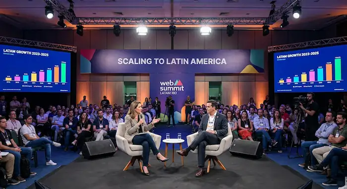Foto do painel no Web Summit Latam Rio: palco com banner "Scaling to Latin America", Maria apresentando ao lado do diretor de inovação do Grupo Bimbo, plateia de ~300 pessoas, telas com dados de crescimento.